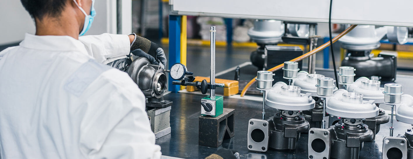 Technician inspecting quality turbocharger components at a turbocharger manufacturing facility